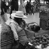 ohne Titel. (Ältere Frau mit spielenden Kindern auf  dem Bordstein, neben ihrem zum Verkauf ausgebreiteten Gemüse sitzend).